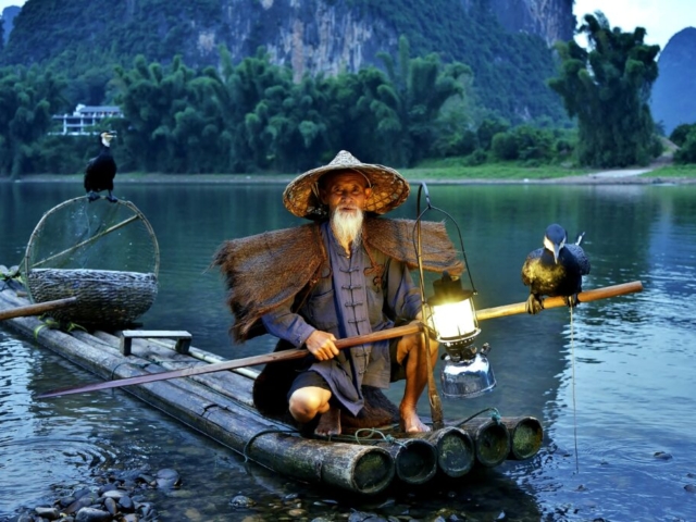 Cormorant fisherman "The Younger Huang (yellow)" in sunset at Li River, Yangshuo, Guangxi, China