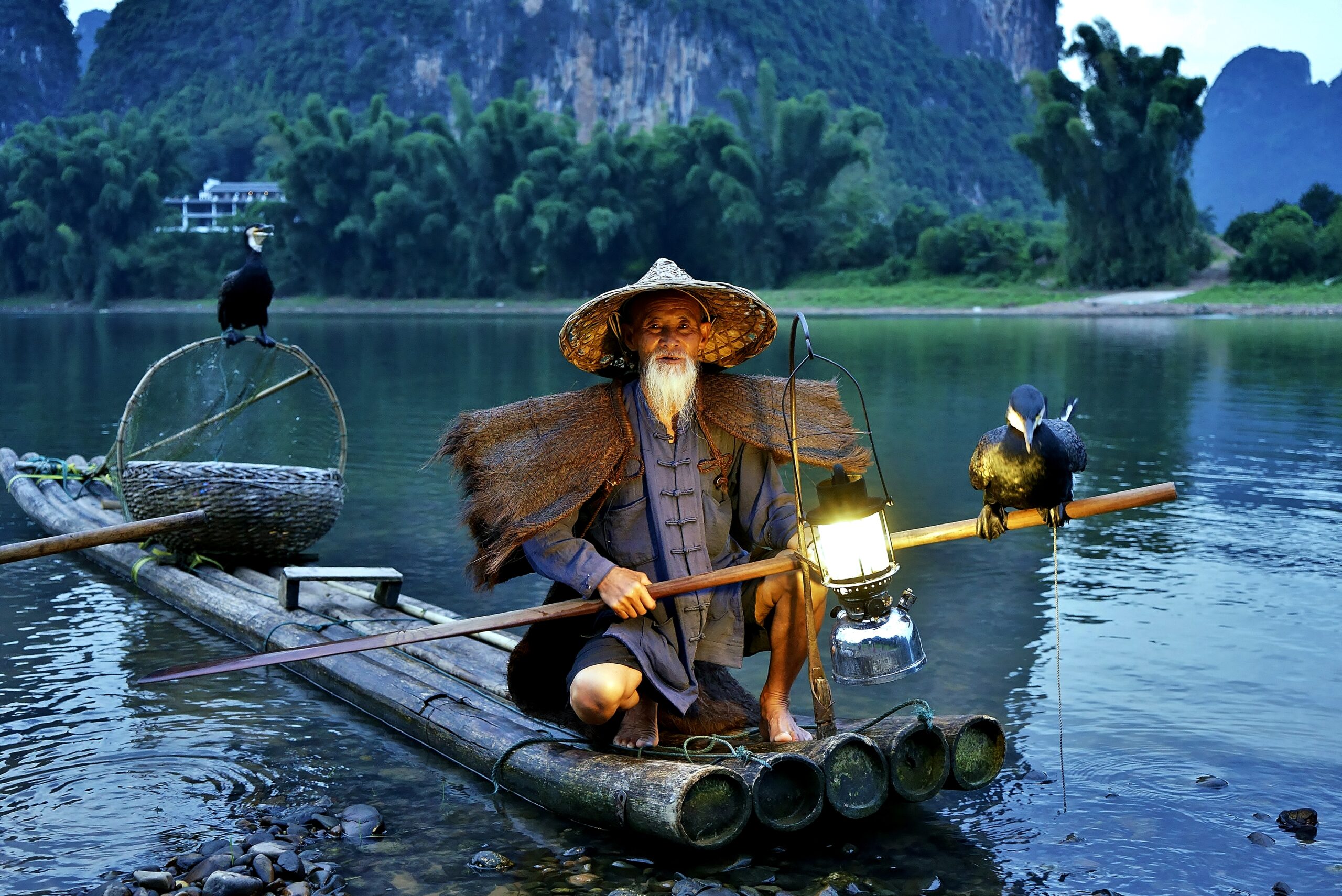 Cormorant fisherman "The Younger Huang (yellow)" in sunset at Li River, Yangshuo, Guangxi, China