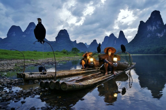 Cormorant fisherman brothers Huang in sunset at Li River, Yangshuo, Guangxi, China